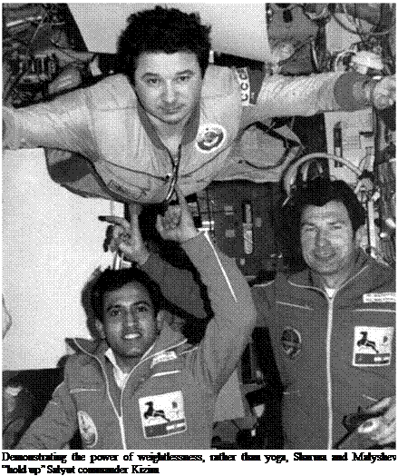 Подпись: Demonstrating the power of weightlessness, rather than yoga, Sharma and Malyshev “hold up” Salyut commander Kizim 