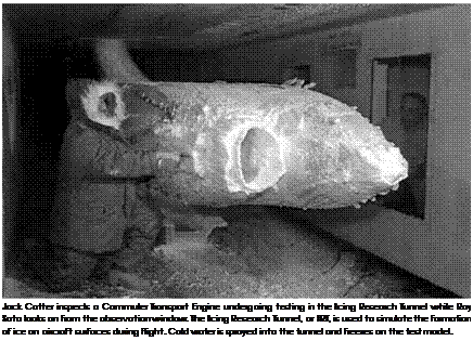 Подпись: Jack Cotter inspects a Commuter Transport Engine undergoing testing in the Icing Research Tunnel while Ray Soto looks on from the observation window. The Icing Research Tunnel, or IRT, is used to simulate the formation of ice on aircraft surfaces during flight. Cold water is sprayed into the tunnel and freezes on the test model. 